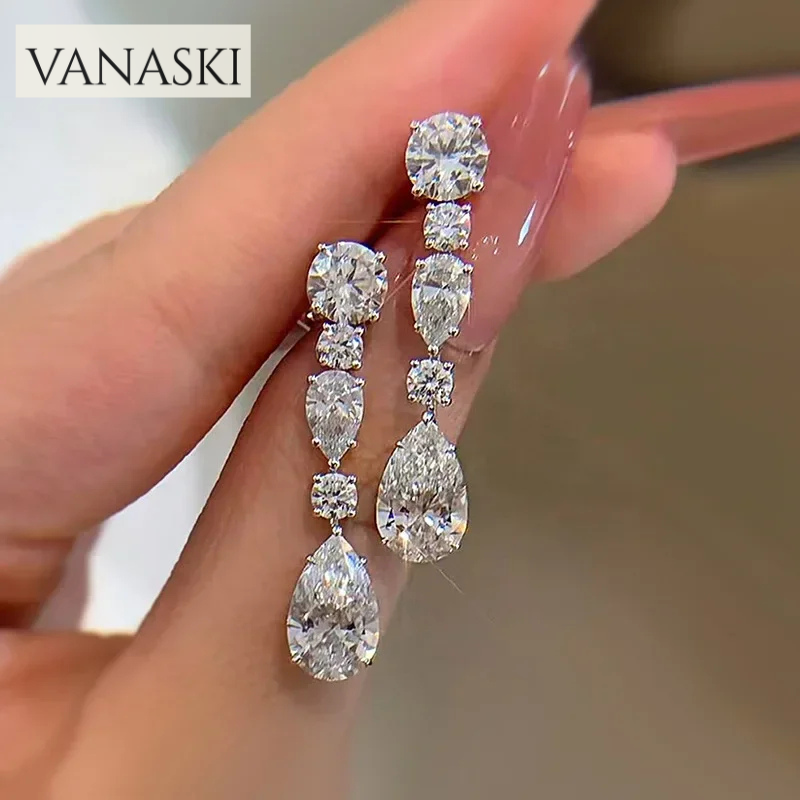 Teardrop-shaped diamond earrings held by a hand with 'VANASKI' branding.