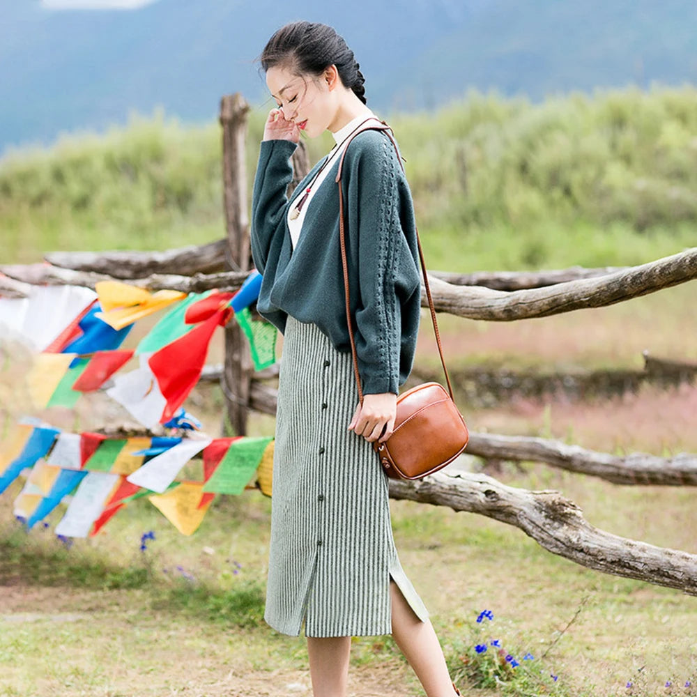 Woman standing outdoors with colorful flags and a wooden fence in the background