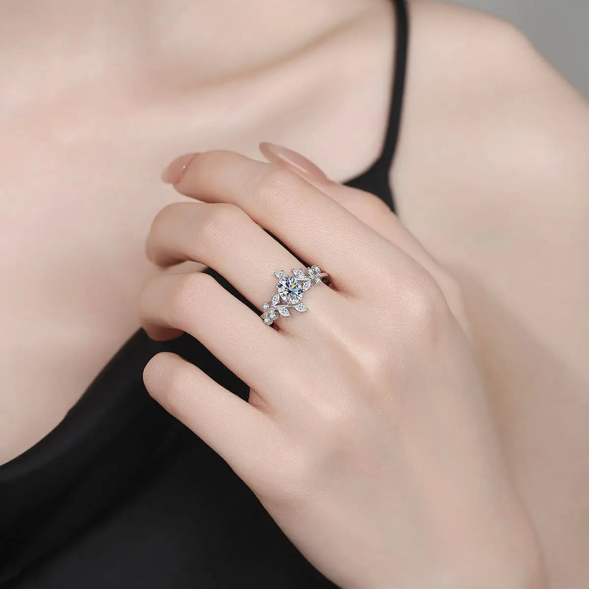 Close-up of a hand wearing a silver ring with a diamond on a neutral background