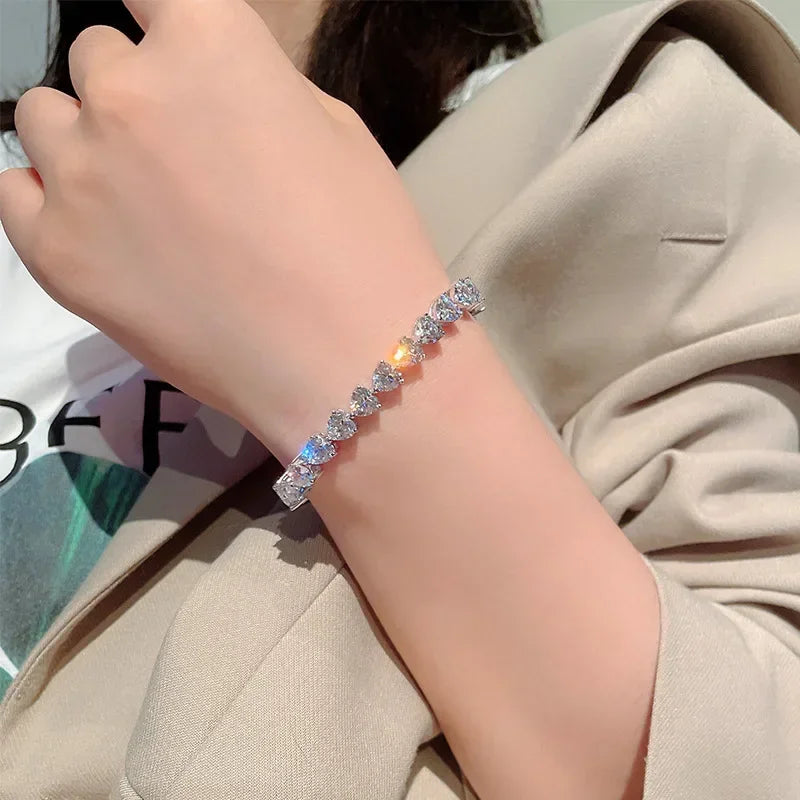 Close-up of a hand wearing a silver bracelet with gemstones, against a neutral background.