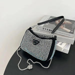 Black handbag with white embellishments on a black surface with books in the background