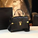 Black textured handbag with gold accents on a light surface.
