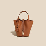 Brown leather handbag with a smiley face charm on a beige background