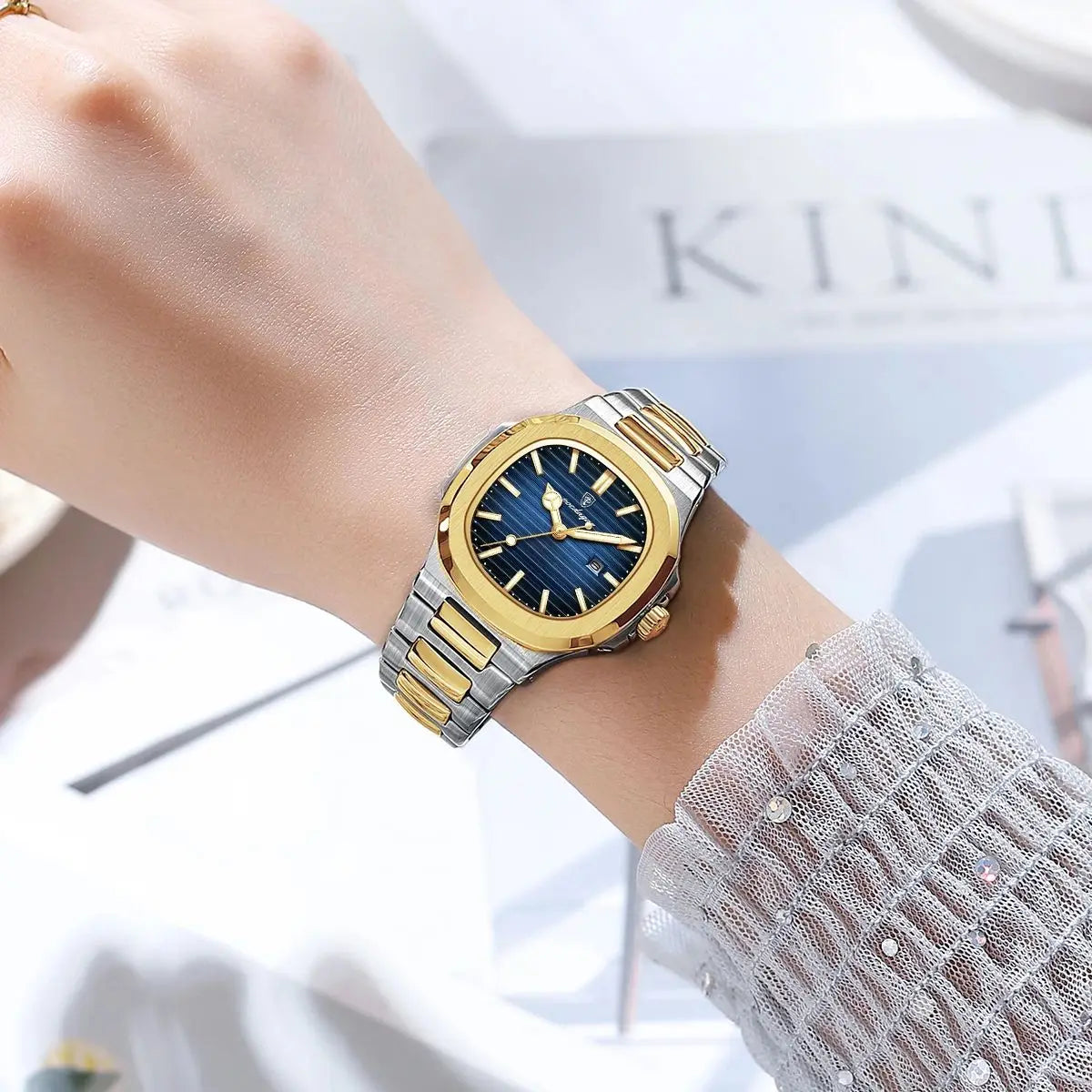 Gold and silver watch on a wrist with a blurred background