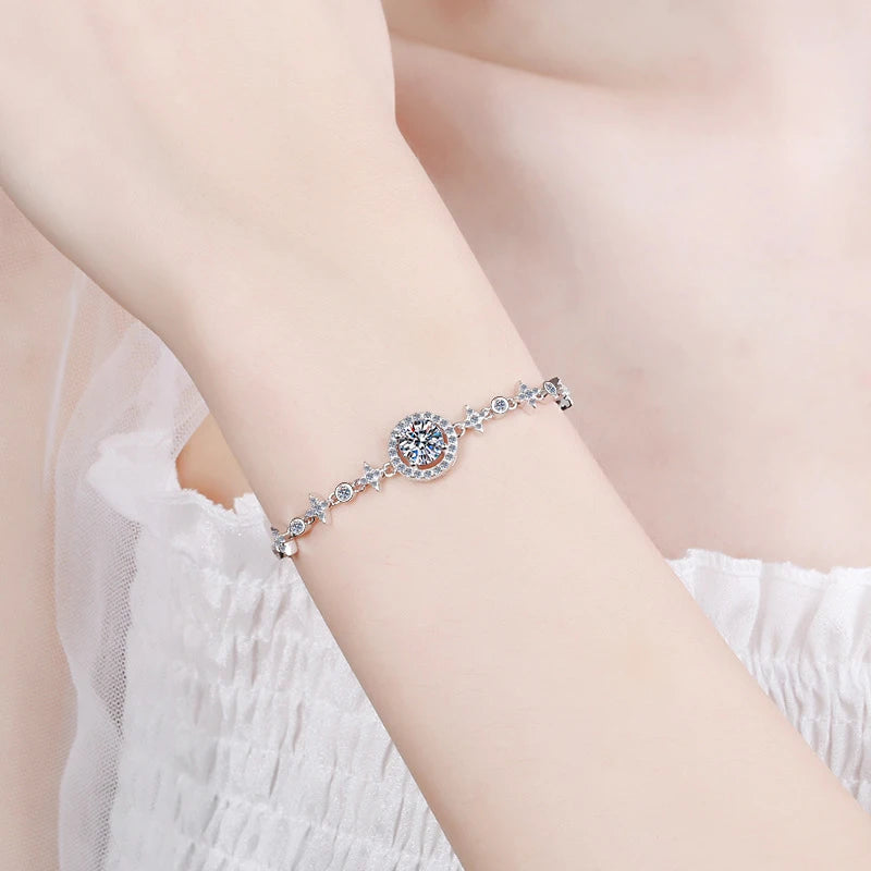 Silver bracelet with a large central gemstone on a person's wrist against a soft pink background