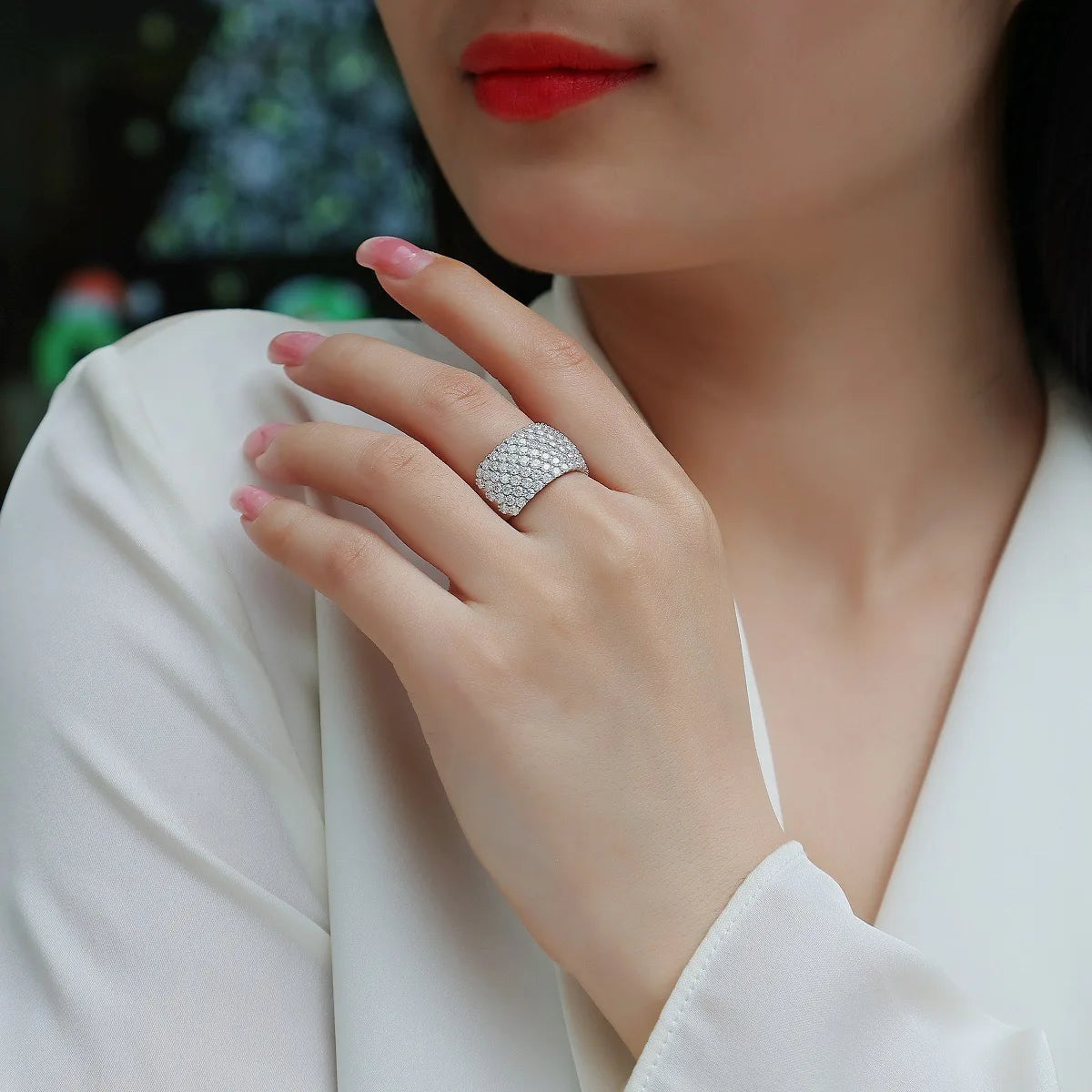 Close-up of a hand wearing a silver ring with a blurred background
