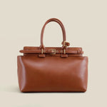 Brown leather handbag with gold accents on a beige background