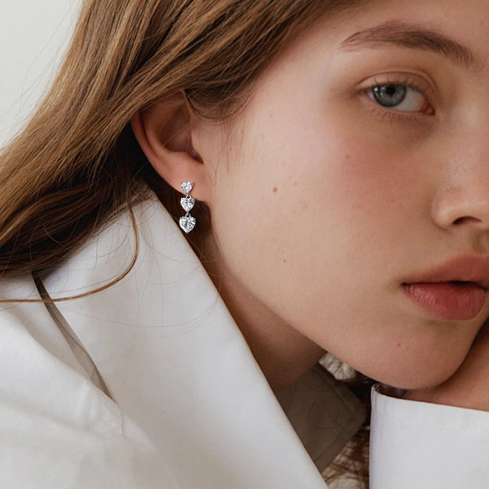 Close-up of a woman wearing heart-shaped earrings with a neutral background