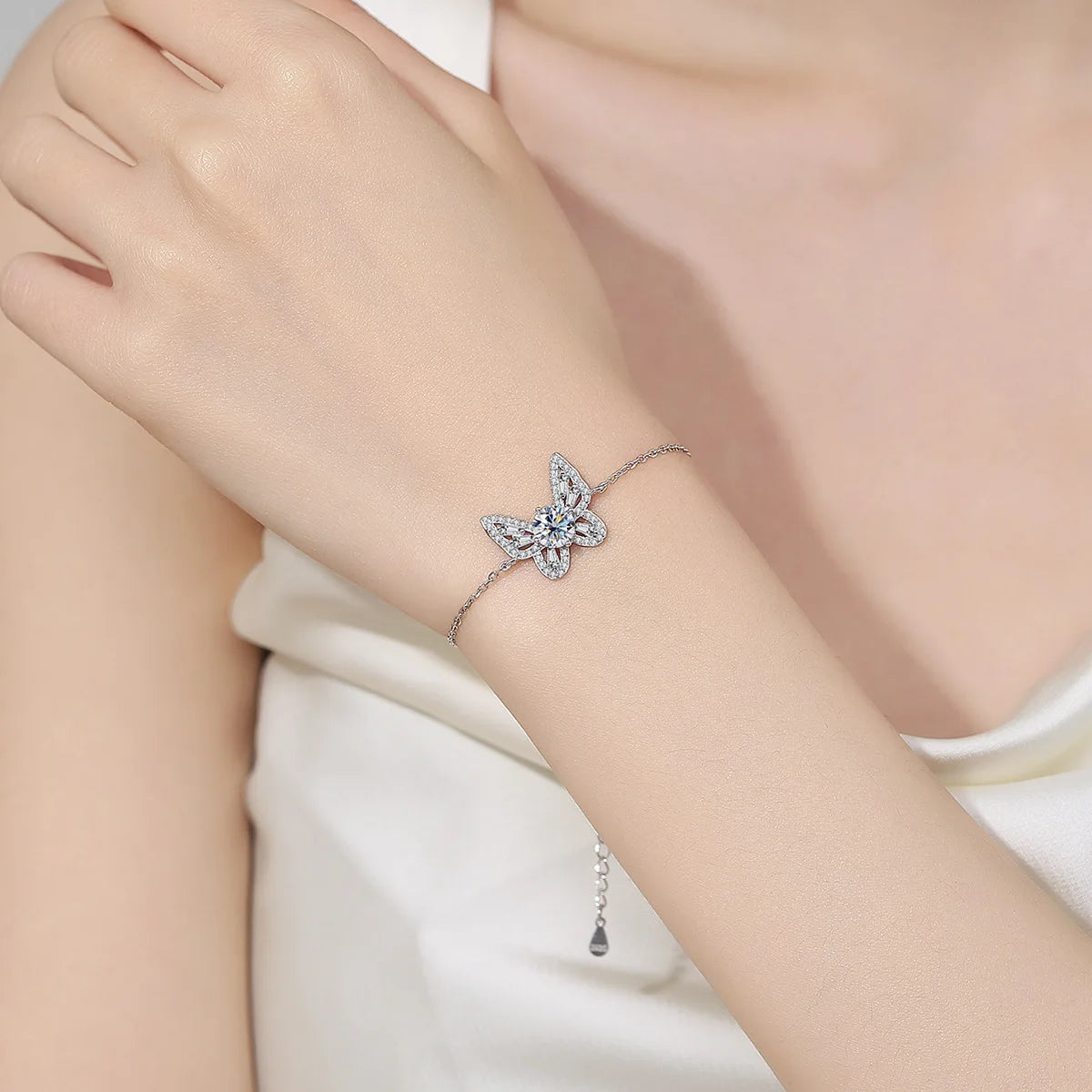 Silver bracelet with a starfish design on a person's wrist against a neutral background