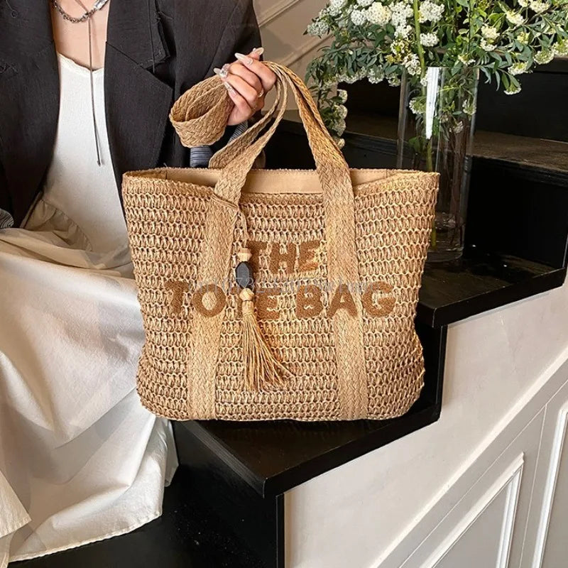Woven tote bag with 'THE TOTE BAG' text held by a person in an indoor setting.
