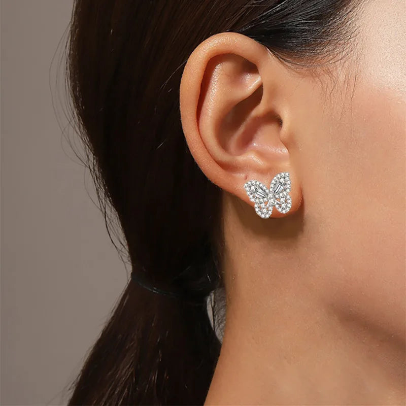 Butterfly-shaped earrings worn by a person with a neutral background