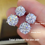 Pair of diamond earrings held between fingers with size labels on a blurred background