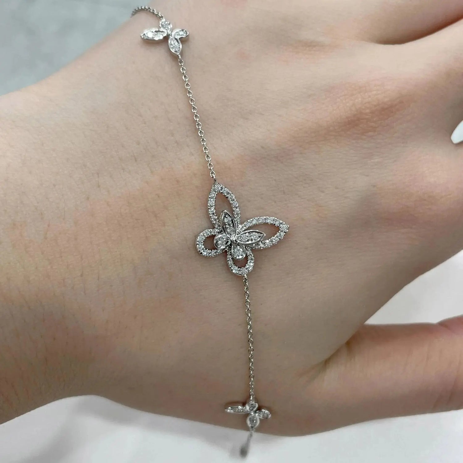 Silver butterfly bracelet on a wrist against a neutral background