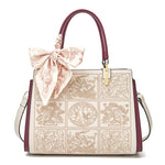 Designer handbag with intricate patterns and a decorative bow on a white background
