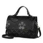 Black leather handbag with floral design on a white background