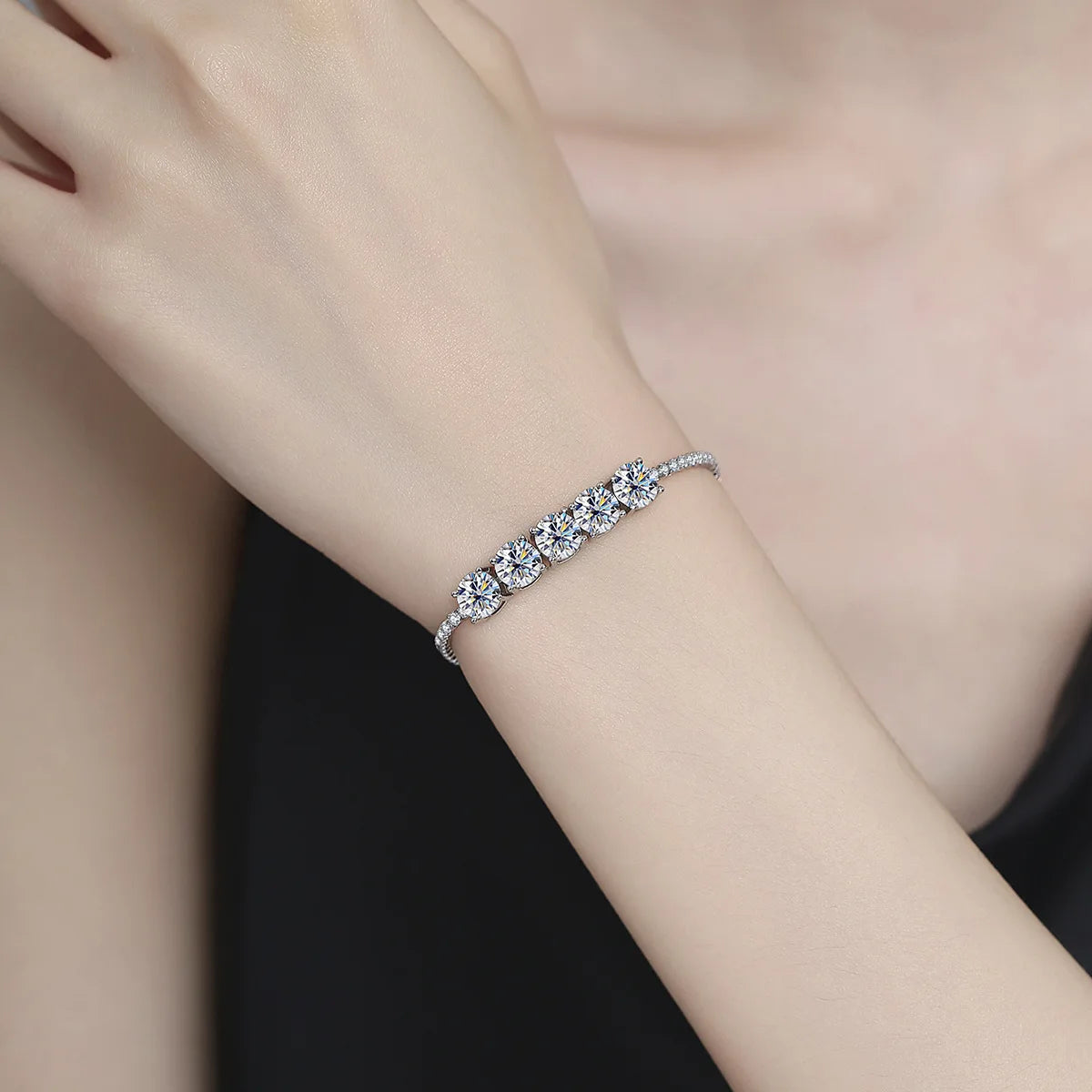Silver bracelet on a person's wrist against a neutral background