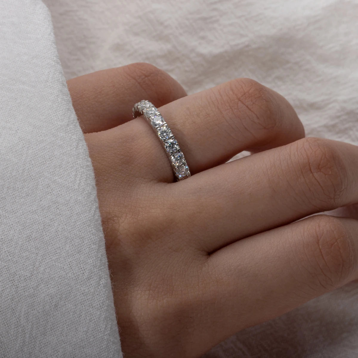 Close-up of a hand wearing a diamond ring on a soft white background