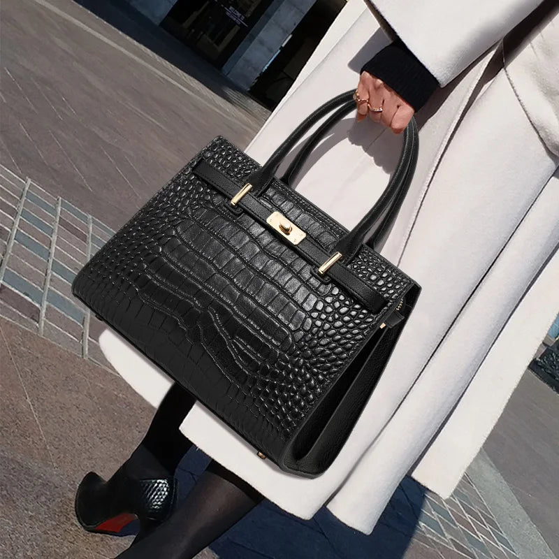 Person holding a black crocodile-patterned handbag with a gold clasp.
