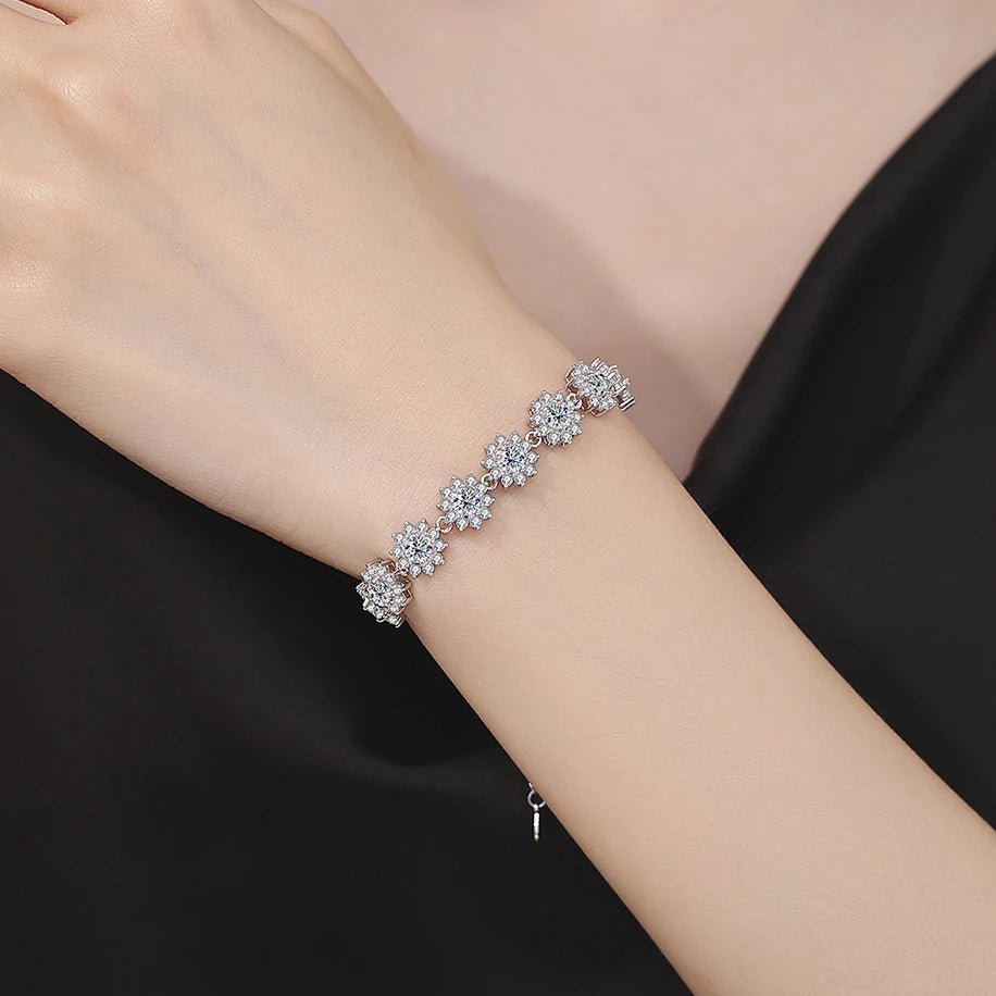 Silver bracelet with floral design on a wrist against a black background