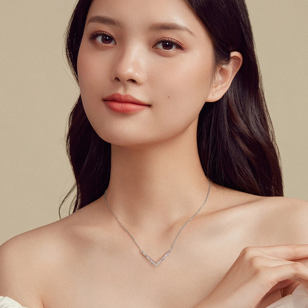 Woman wearing a delicate necklace against a neutral background