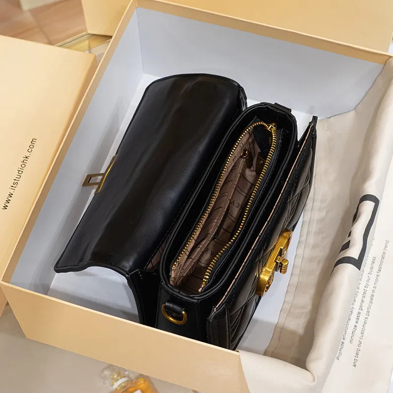 Black handbag with gold accents in a beige box