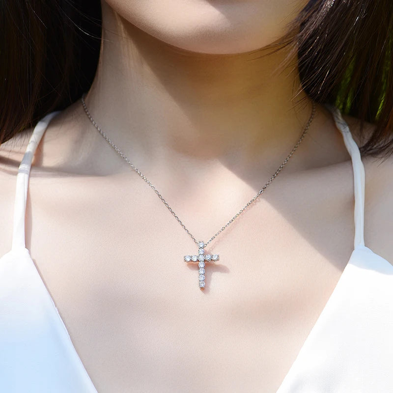 Necklace with a cross pendant worn by a person in a white top