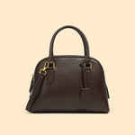 Brown handbag with gold hardware on a beige background