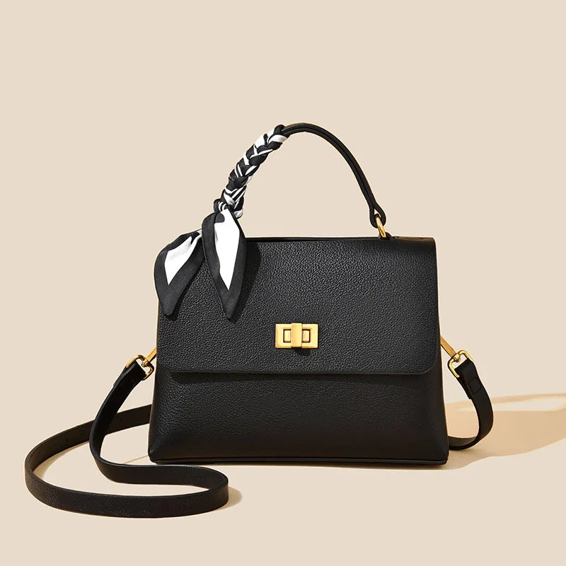Black handbag with a gold clasp on a beige background