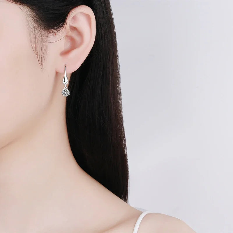 Silver earring worn by a model on a plain background