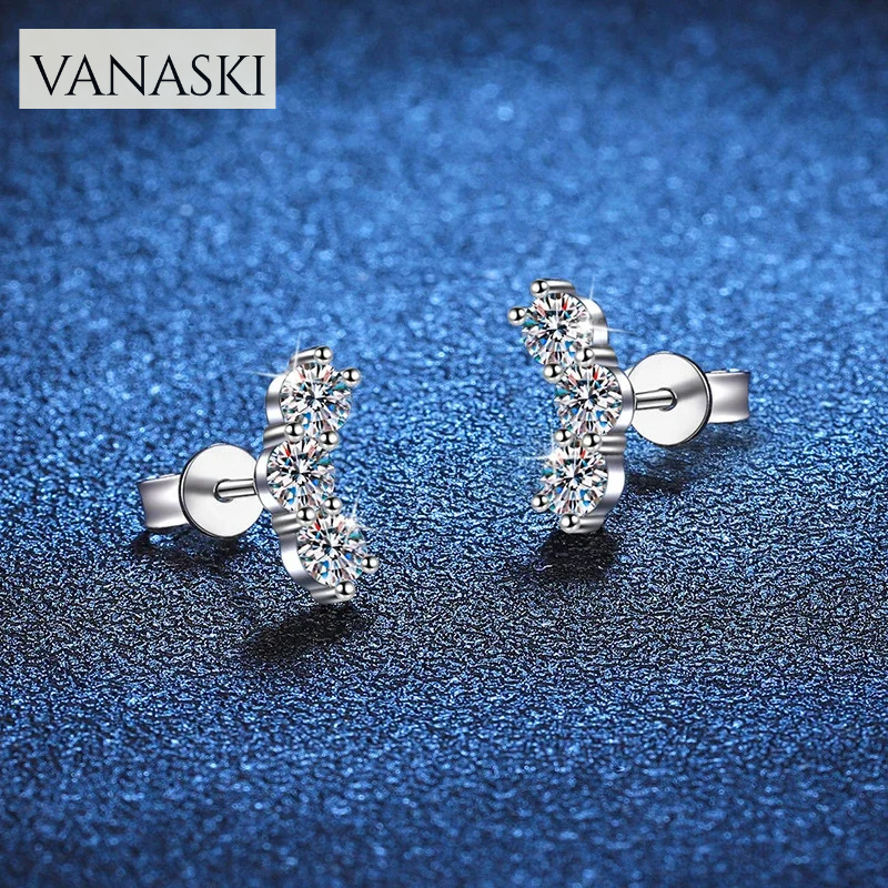 Silver earrings with clear gemstones on a blue textured background, featuring the Vanaski brand.