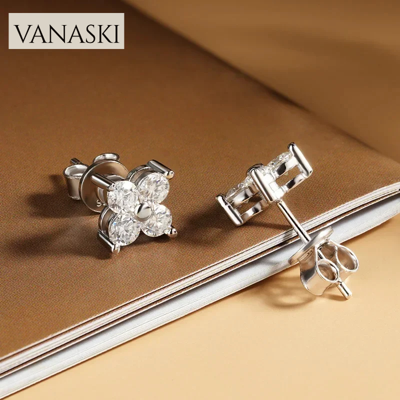 Silver earrings with clear stones on a brown fabric background, featuring the Vanaski brand.