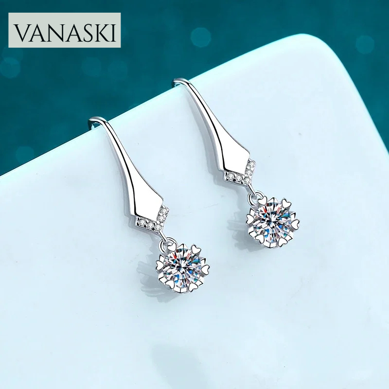 Silver earrings with gemstones on a light blue background, featuring the VANASKI brand.