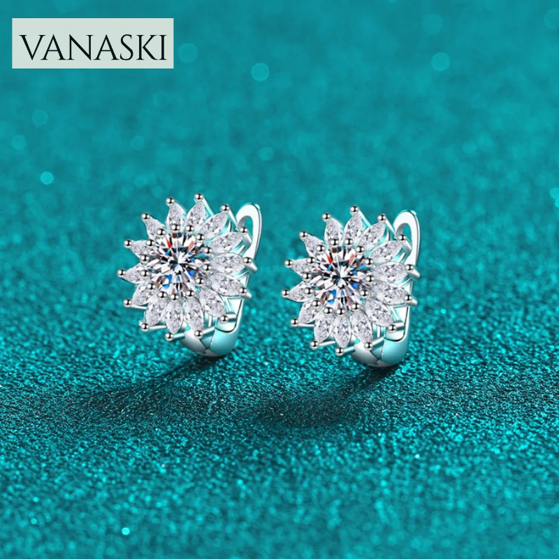 Pair of silver star-shaped earrings with clear stones on a teal background, featuring the Vanaski brand.