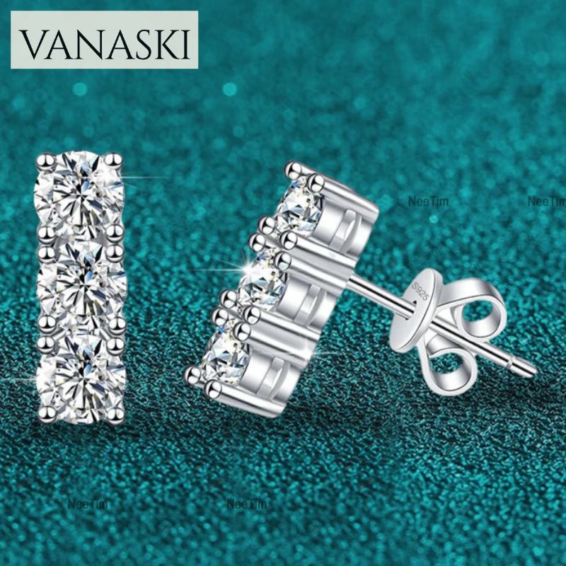 Silver stud earrings with clear gemstones on a teal background, featuring the Vanaski brand.