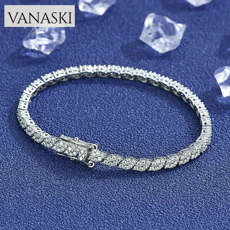 Silver bracelet with clear stones on a blue textured background, featuring the brand 'VANASKI'.