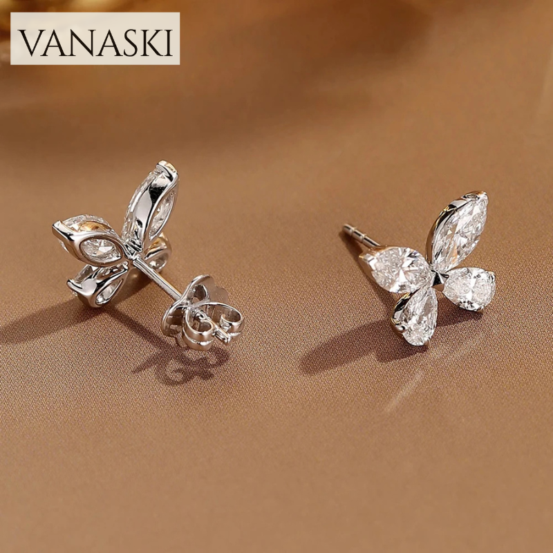 Butterfly-shaped earrings withVanaski branding on a brown background