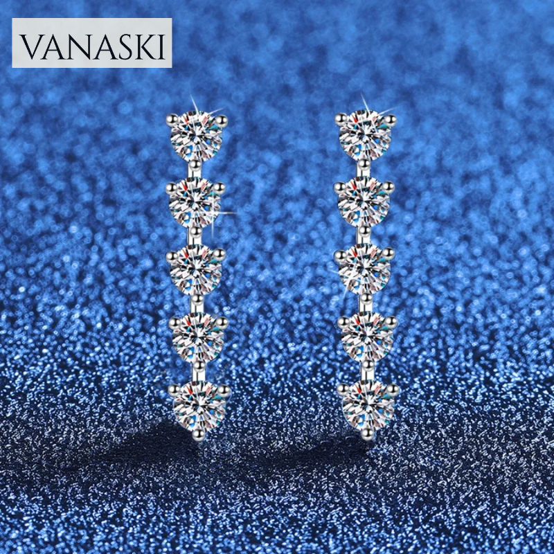 Pair of Vanaski earrings on a blue glittery background