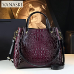 Purple textured handbag with gold accents on a white surface, Vanaski brand visible.