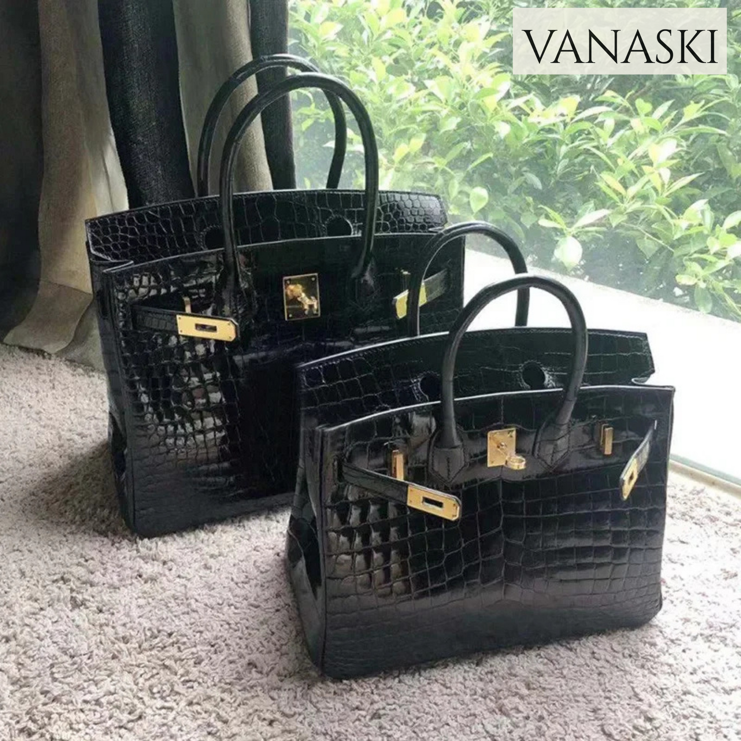Two black crocodile-patterned handbags with gold hardware on a carpeted floor, with 'VANASKI' branding.