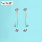 Silver earrings with dangling beads on a light blue background, featuring the VANASKI brand.