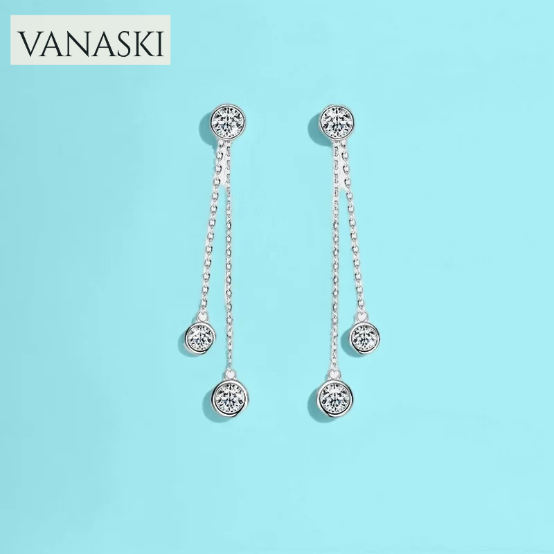 Silver earrings with dangling beads on a light blue background, featuring the VANASKI brand.