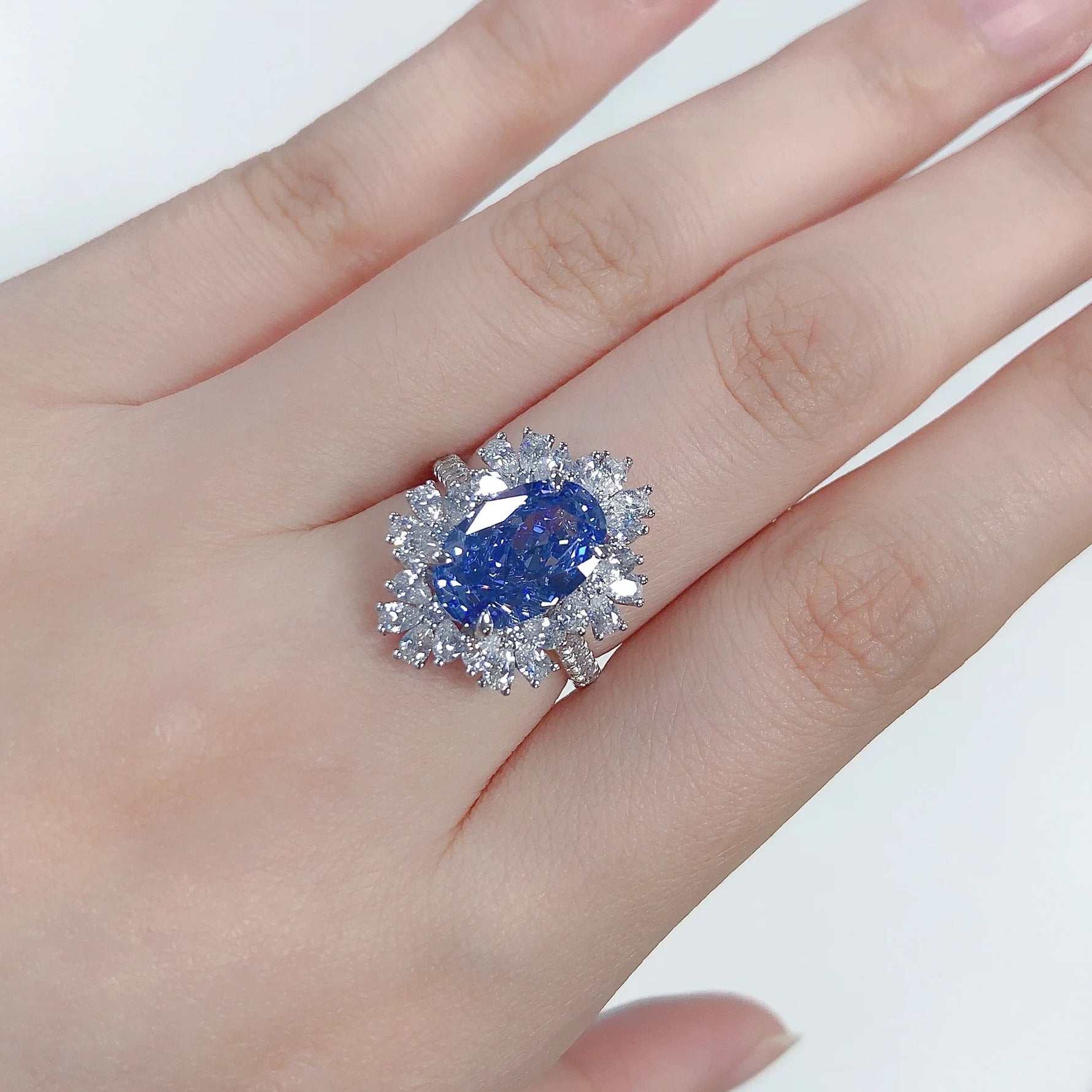 Ring with a blue gemstone on a hand against a white background