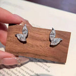 Pair of silver leaf-shaped earrings on a wooden display card.
