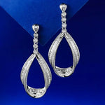 Pair of silver teardrop earrings with clear stones on a blue background