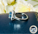 Silver ring with blue gemstones on a dark surface with floral background