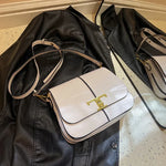 White handbag with gold accents on a black leather jacket