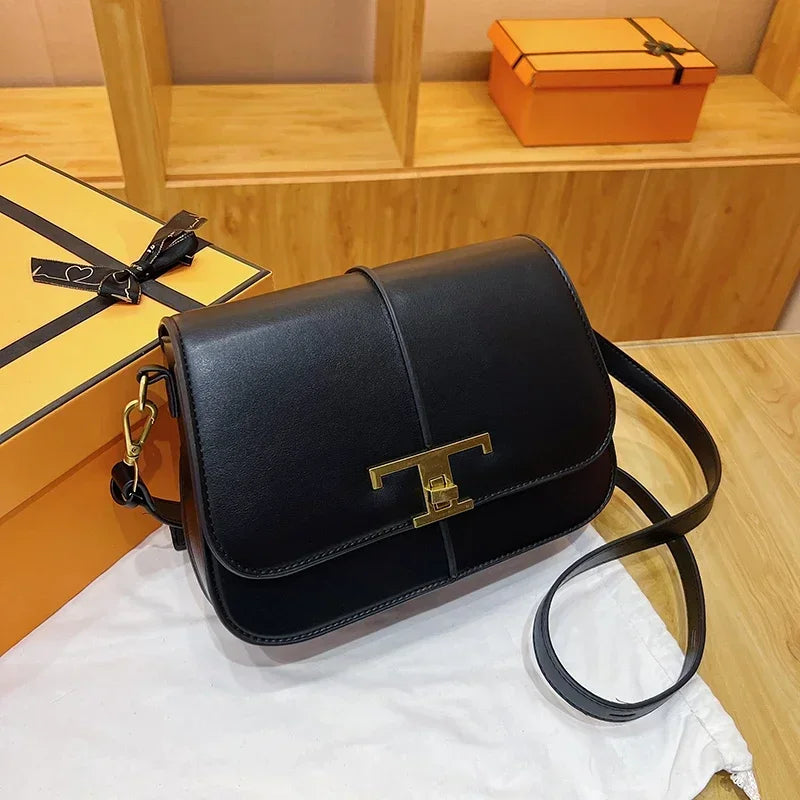 Black handbag with gold clasp on a white cloth, with yellow boxes in the background.