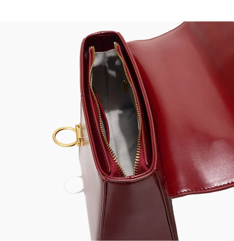 Close-up of a red handbag with gold zipper and handle on a white background