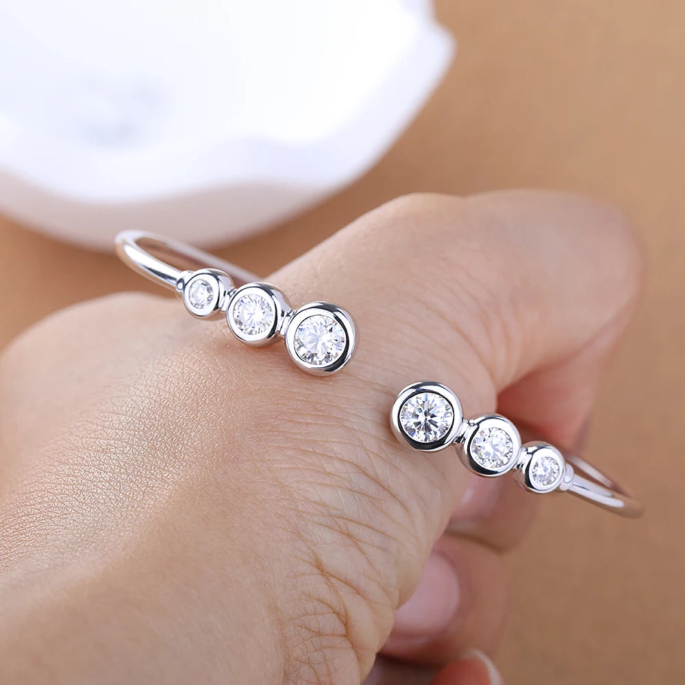 Silver ring with round gemstones on a hand against a neutral background
