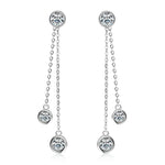 Pair of silver earrings with chain and round gemstones on a white background